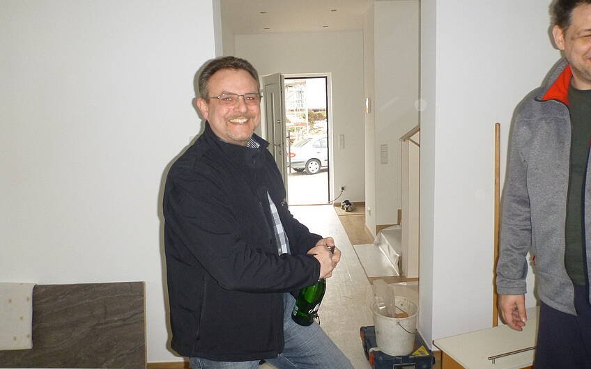 Stephan Rübenacker beim Öffnen der Sektflasche bei der Hausübergabe in der individuell geplanten Kern-Haus-Stadtvilla Novo in Angelbachtal