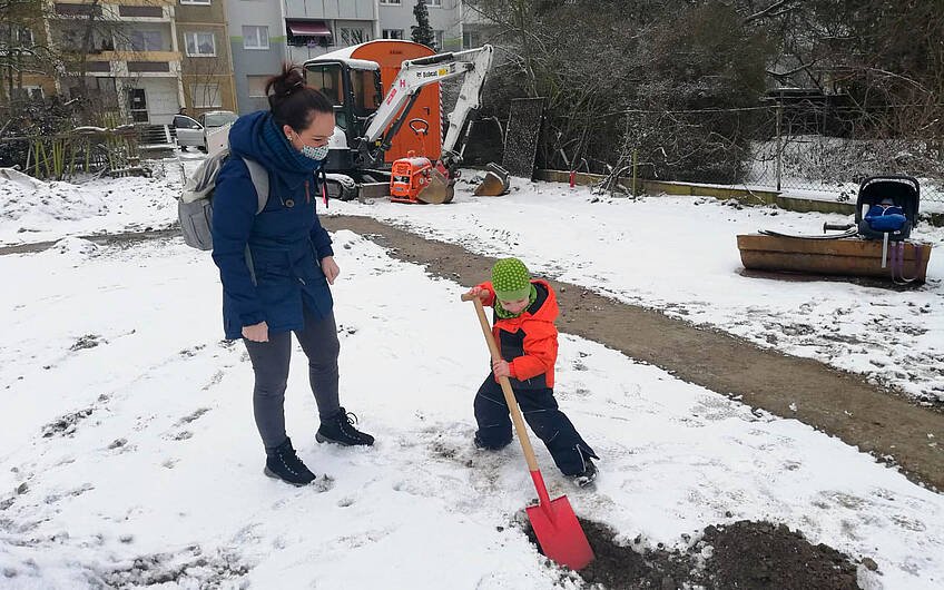 Kind mit Bauherrin beim Graben des Loches für Grundsteinkassette für Kern-HAus in Halle Ammendorf