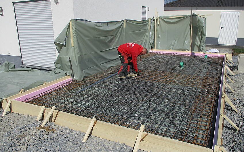 Bevor die Bodenplatte mit Beton verfüllt wird, müssen Eisenmatten verlegt werden.