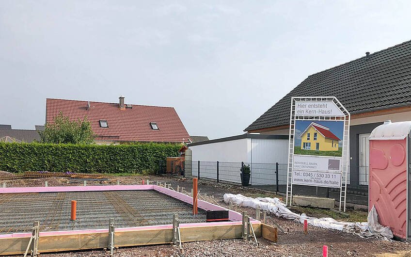Vorbereitung der Bodenplatte und Bauschild für Kern-Haus mit Pultdach in Halle Wörmlitz
