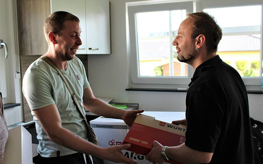 Kern-Haus-Bauleiter Yves Balster übergibt dem Bauherren einen Dübelkoffer der Firma Würth