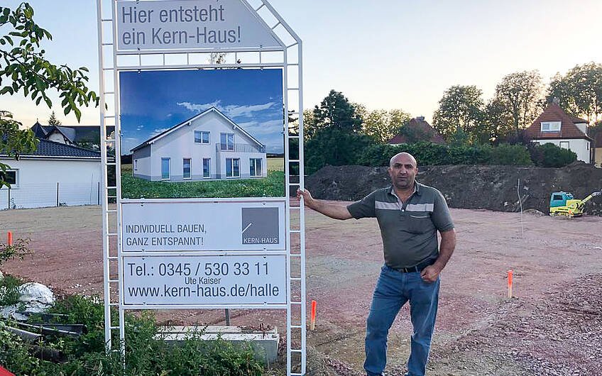Bauherr mit Bauschild für Kern-Haus Bungalow in Halle Ammendorf