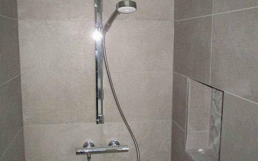 Eine praktische Ablagefläche für Duschutensilien und eine stilvolle Duscharmatur sorgen für reines Duschvergnügen.