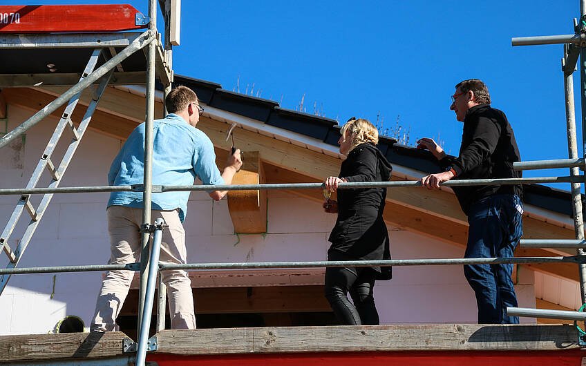 Bauherren beim Einschlagen des letzten Nagels in Dachstuhl