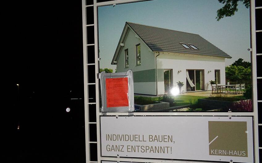 Bauschild mit roten Punkt für das individuell geplante Einfamilienhaus Signum von Kern-Haus in Römerberg