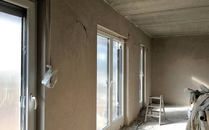 Zu sehen sind Fenster sowie die verputzten Wände im Einfamilienhaus in Magdeburg. Kern-Haus baut individuell.