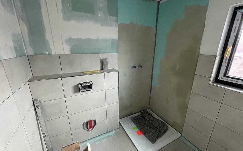 Im Badezimmer wurden die Wände gefliest und die Duschtasse eingebaut.