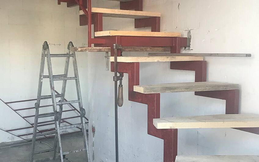 Die Treppe wird montiert und mit Baustufen versehen. Kurz vor Einzug wird die Stahlkonstruktion farblich gestaltet und die Trittstufen montiert