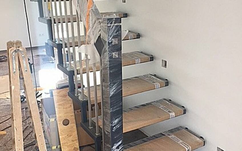 Montage der Holzstufen und des Geländers an Treppe