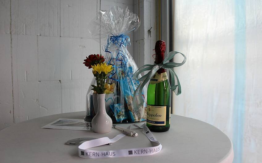 Sekt, Süßigkeiten und eine Blume stehen auf einem Tisch. Zum Rohbaufest bekommen die Bauherren Geschenke von Familie und Freunden.
