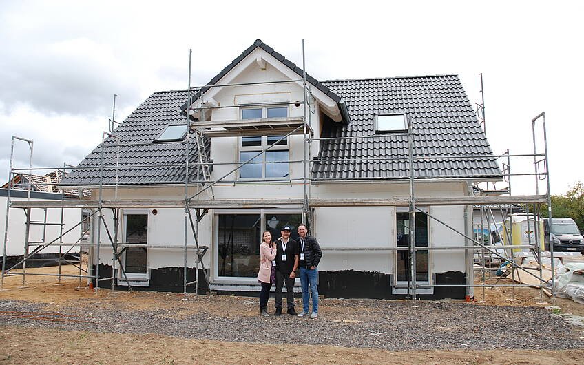 Die Bauherren mit Baufachberater Michael Zettelmeyer vor ihrem zukünftigen zu Hause