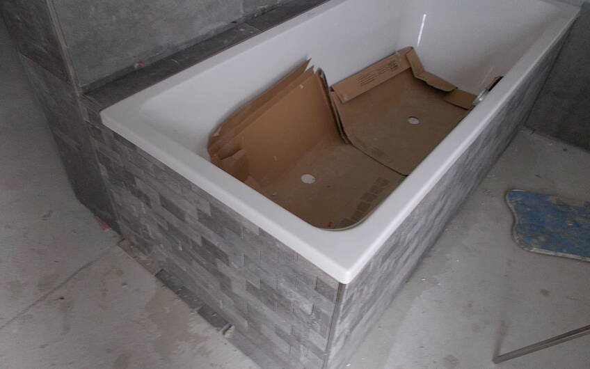 Geflieste Badewanne im Badezimmer des individuell geplanten Einfamilienhauses Signum von Kern-Haus in Einselthum