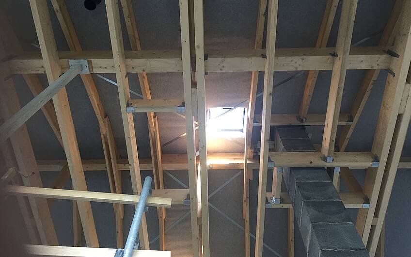 Innenansicht des Dachstuhls mit Kamin im Kern-Haus-Rohbau