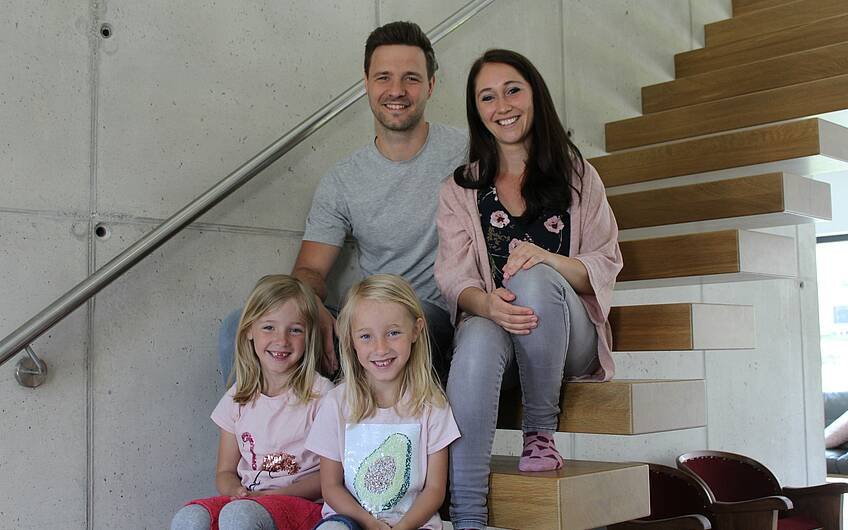Familie sitzt auf freischwebender Treppe in ihrem Bauhaus-ein Kern-Haus