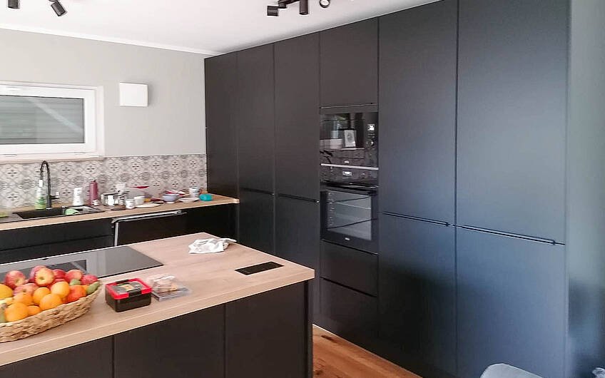 schwarze Küchenzeile mit Insel und Holz in Küche des Kern-Haus Modus in Halle Giebichenstein