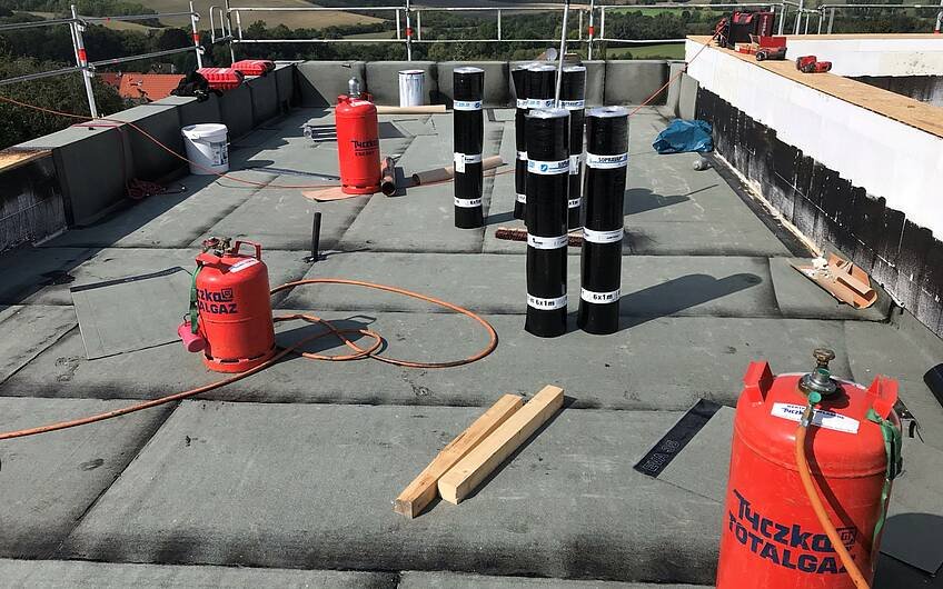 Um das Dach ordnungsgemäß abzudichten, werden nach einem Voranstrich Bitumenbahnen verlegt.