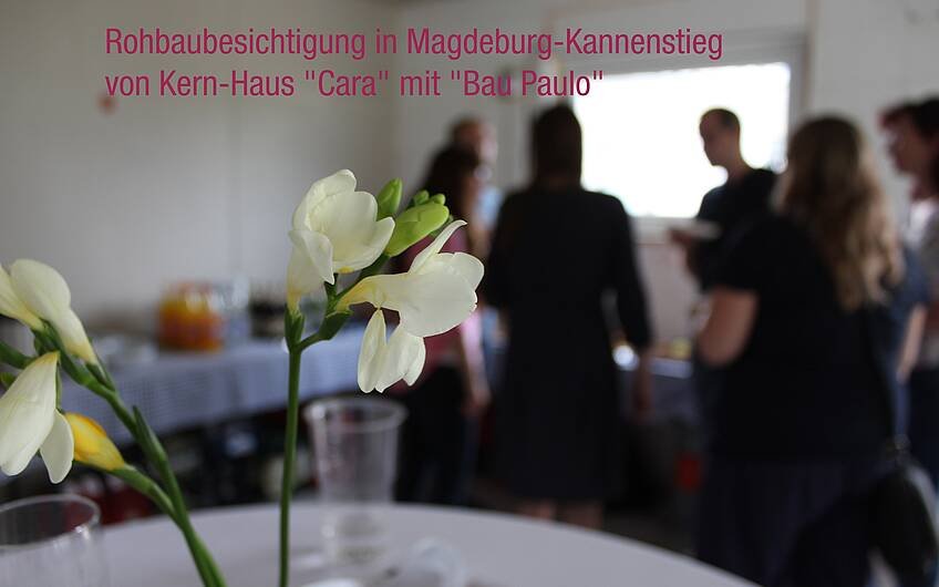 Im Vordergrund Blumen, im Hintergrund Menschen beim Rohbaufest in Magdeburg