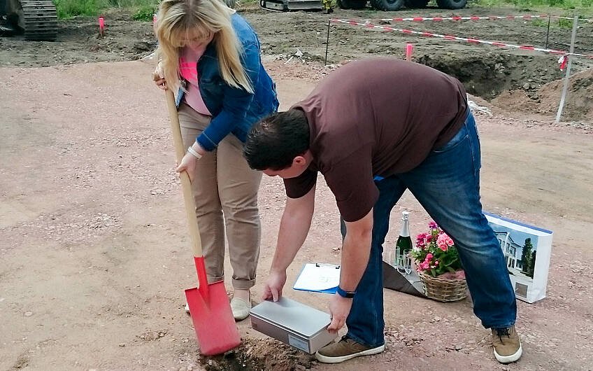 Bauherrin gräbt Loch für Grundsteinkassette bei Grundsteinlegung