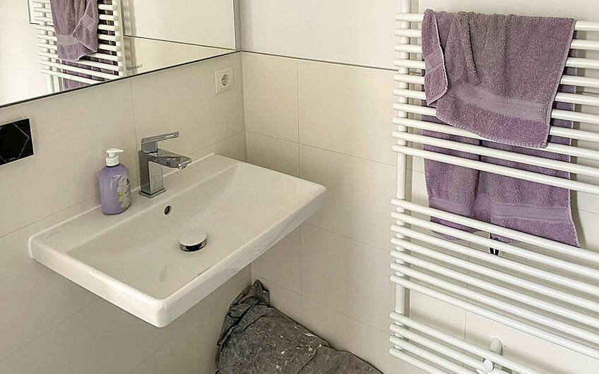 Gästebad mit hellen Fliesen sowie Waschbecken und Handtuchheizkörper in Kern-Haus Stadtvilla in Halle Reideburg