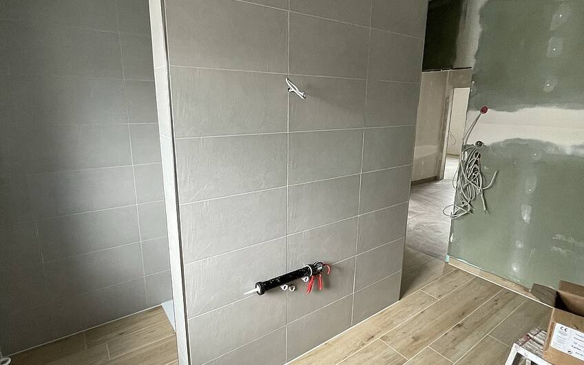 Im Badezimmer wurde eine T-Lösung geschaffen, hinter der Wand befindet sich die Dusche.