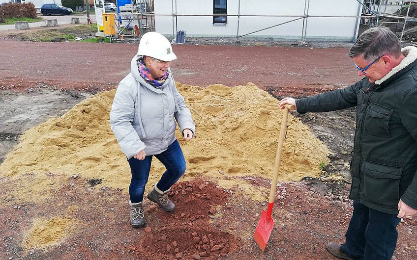 Bauherrin mit Bauhelm und Spaten für Grundsteinlegung eines Kern-Haus Loop Classic in  Halle Reideburg