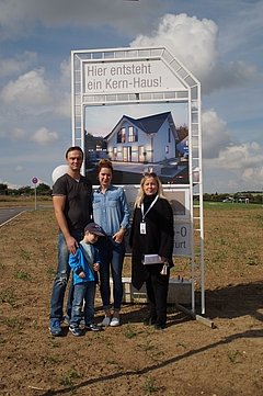 Bauherren vor Bauschild mit dem Kern-Haus Komfort Baugebiet Erfurt-Marbach