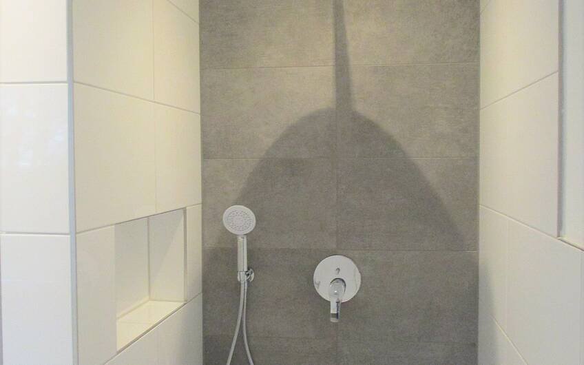 Die bodentiefe Dusche mit Wandnische für Duschutensilien und Beleuchtung lässt das Duschen zu einem besonderen Erlebnis werden.