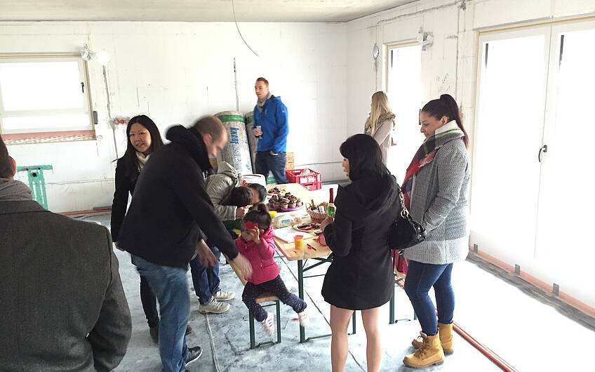 Bauherrin, Kinder und Familienangehörige im Wohnzimmer beim Rohbaufest im individuell geplanten Einfamilienhaus Luna von Kern-Haus in Ludwigshafen