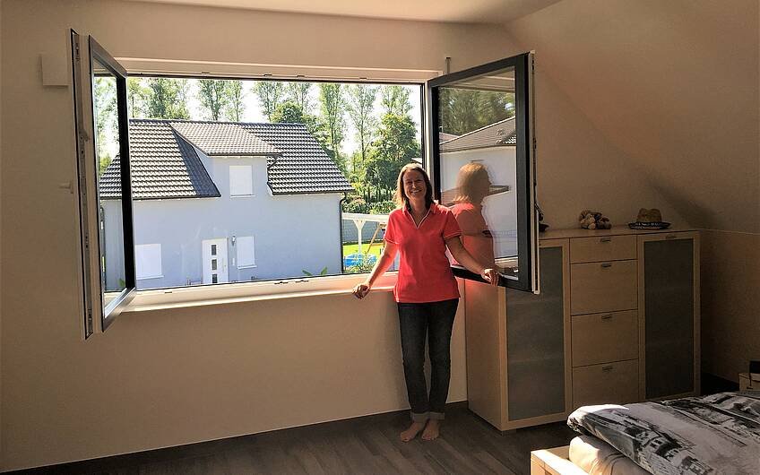Bauherrin am Schlafzimmerfenster im individuell geplanten Einfamilienhaus Luna von Kern-Haus in Dettenheim