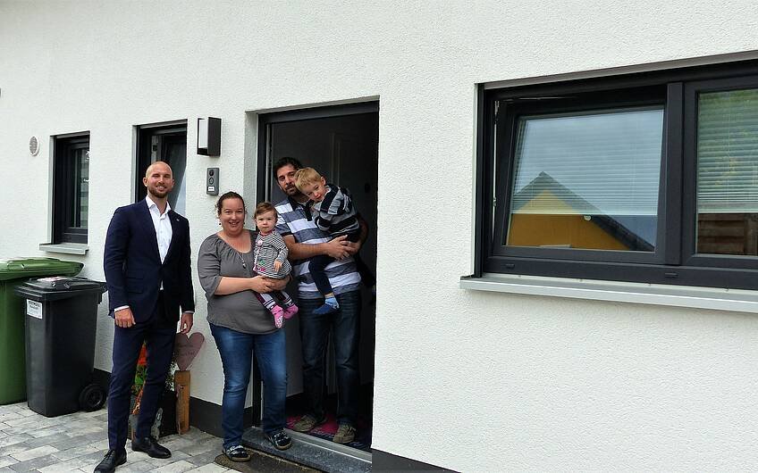 Verkaufsberater Bernd Laatz und Baufamilie an der Haustür des Kern-Hauses Komfort in Linkenheim-Hochstetten