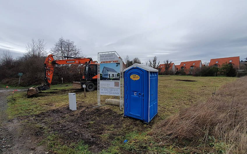 Bagger Bauschild und Baustellentoilette auf Grundstück für Kern-Haus in Braschwitz