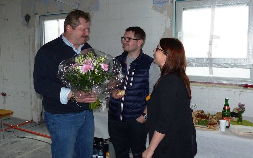 Udo Klosterhalfen überreicht den Bauherren beim Rohbaufest in Einselthum einen großen Blumenstrauß