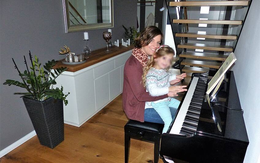 Bauherrin mit Tochter am Klavier in der individuell geplanten Kern-Haus-Stadtvilla Signus in Dettenheim-Rußheim
