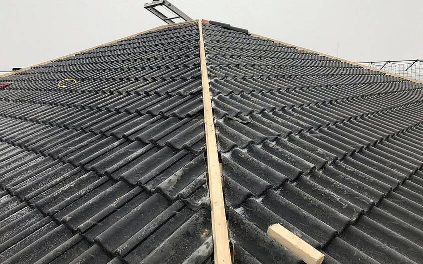 Die Dachdecker verlegen die Dachpfannen.