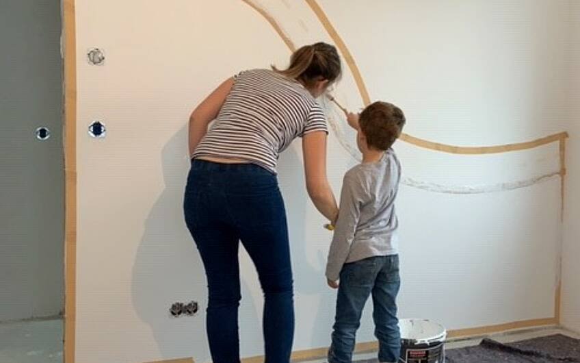 Mama und Kind malern die Wand