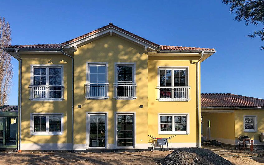 Kern-Haus Aurelio zur HAusübergabe mit gelbem Anstrich in der Terrassenansicht in LEipzig