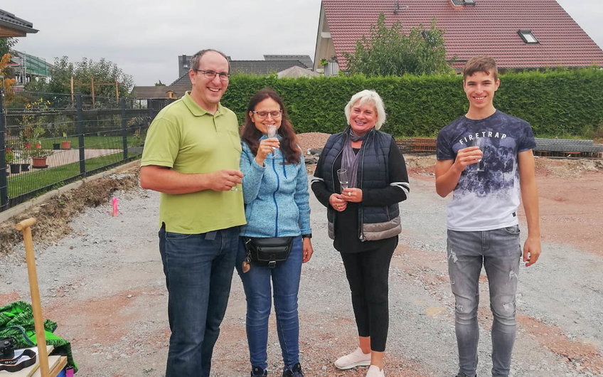 Verkaufsberaterin Ute Kaiser mit Bauherren beim Anstoßen für Kern-HAus Grundsteinlegung in Halle Wörmlitz