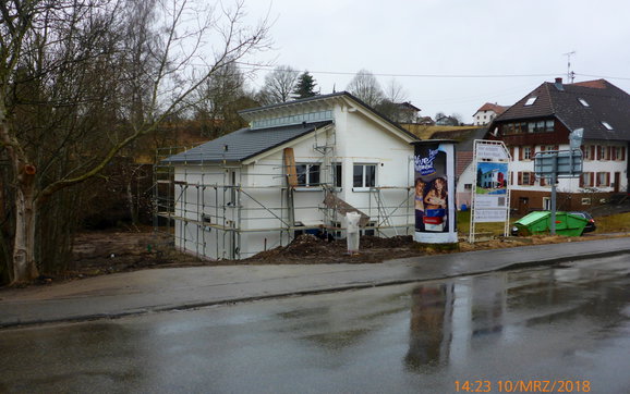 Hausansicht mit eingebauten Fenstern und unverputzter Fassade mit Arbeitsgerüst.