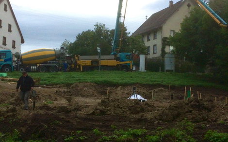 Blick auf Bauplatz mit Fundamentgräben und Betonpumpe im Hintergrund.