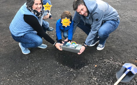 Gemeinsam wird die Grundsteinbox in das Loch gelegt.