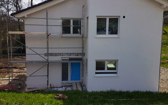 Ansicht Eingangsfront mit Arbeitsgerüst und Montageprofile auf Betonkern.