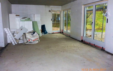 Rohbauraum mit zwei großen Terrassentüren und einem bodentiefen Fenster.