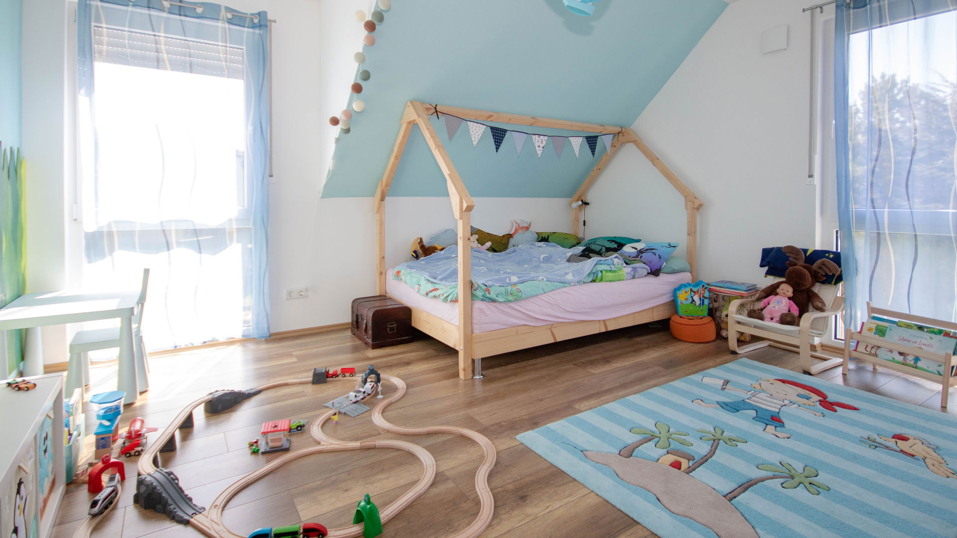 Blaues Kinderzimmer mit Bett, Holzbahn und Teppich in Kern-Haus Luna in Fuchshain
