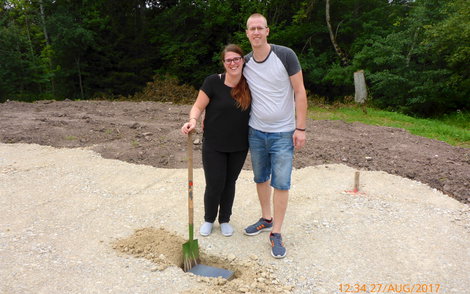 Bauherren mit Spatenstich vor offenem Grundstein.