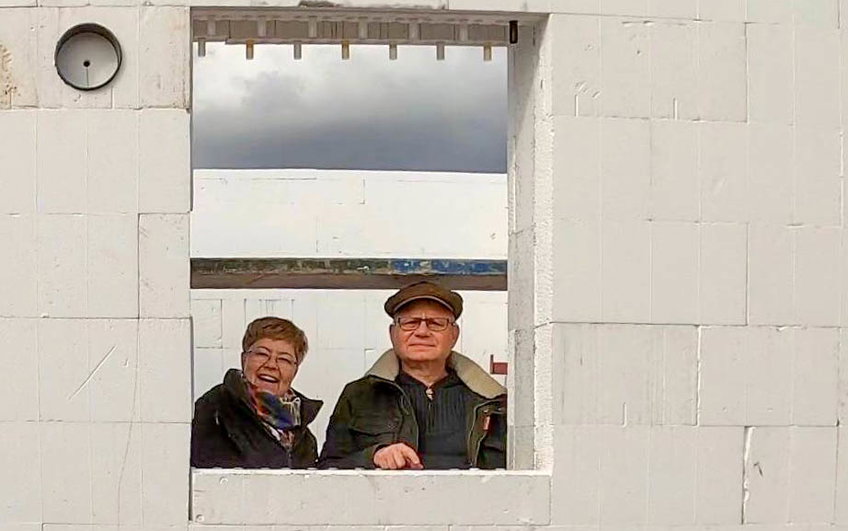 Bauherren blicken durch den Fensterausschnitt ihres Kern-Haus Rohbaus in Halle Reideburg