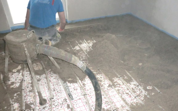 Die vorbereitete Estrichmörtelmischung mit Sand wird zu einer glatten Estrichoberfläche gezogen.