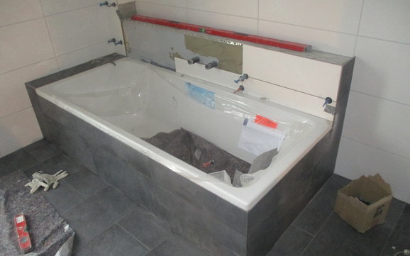Fliesen werden im Bad und um die Badewanne verlegt.