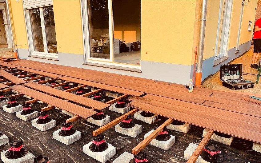 Nachdem die Bauherren in Eigenregie die Unterkonstruktion der Terrasse gestellt haben, werden die Planke verlegt.