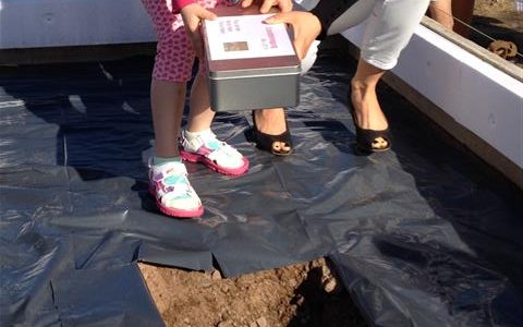 Die Bauherrin und ihre Tochter legen die Kiste ist geschaufelte Loch