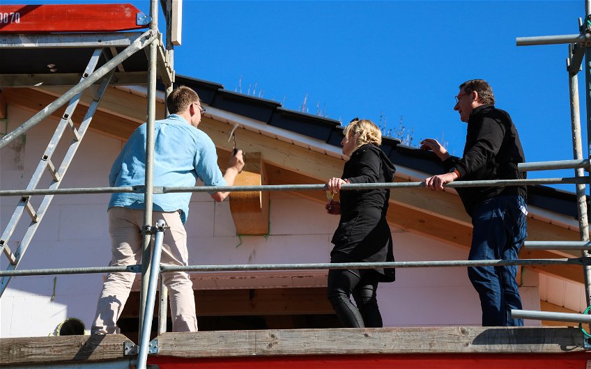 Bauherren beim Einschlagen des letzten Nagels in Dachstuhl